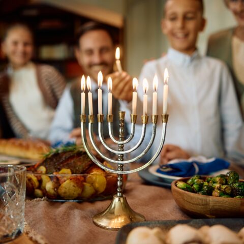 A family lights the last candle on a menorah.