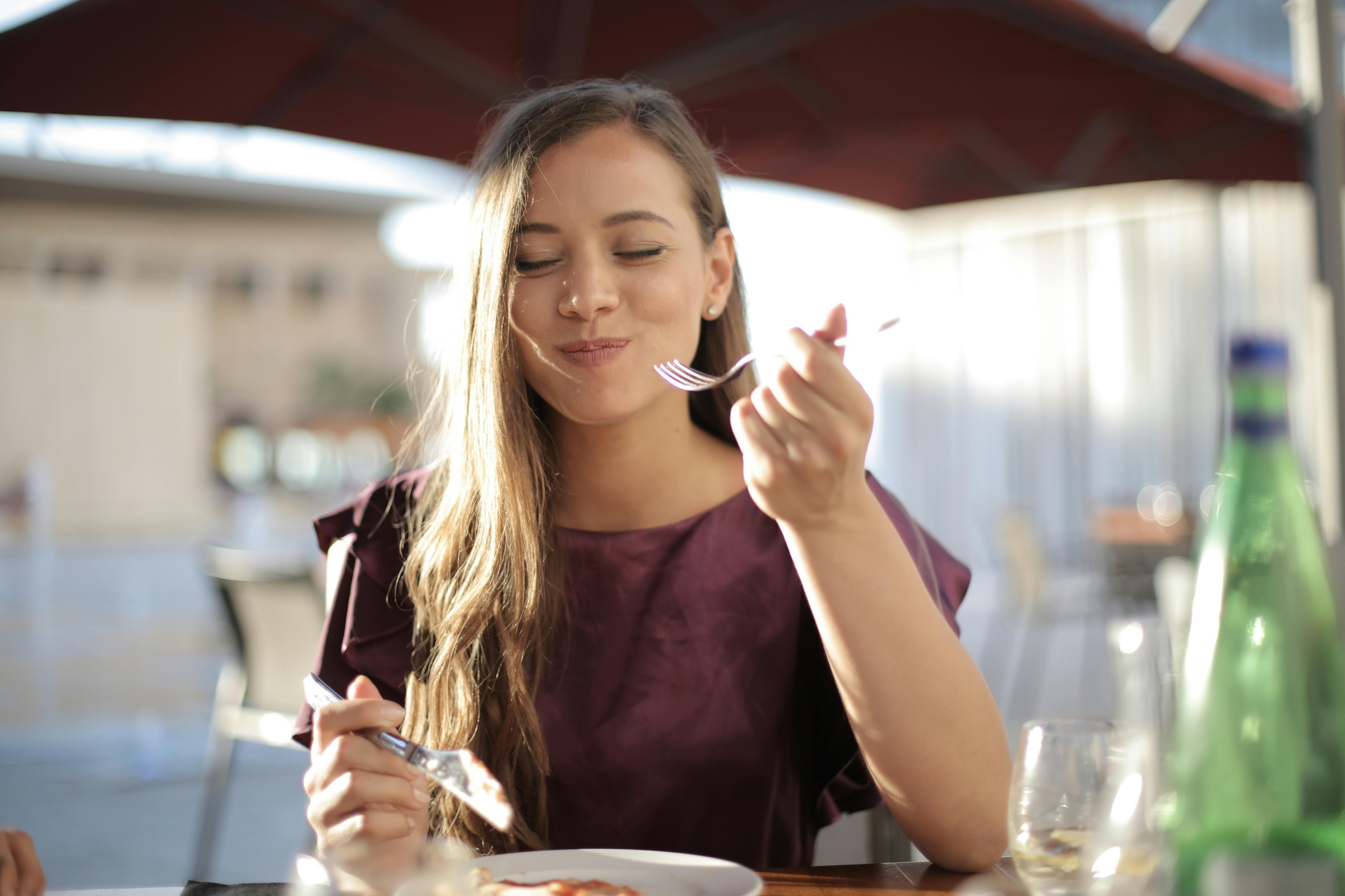 Lady tasting her lunch at a table, smiling.