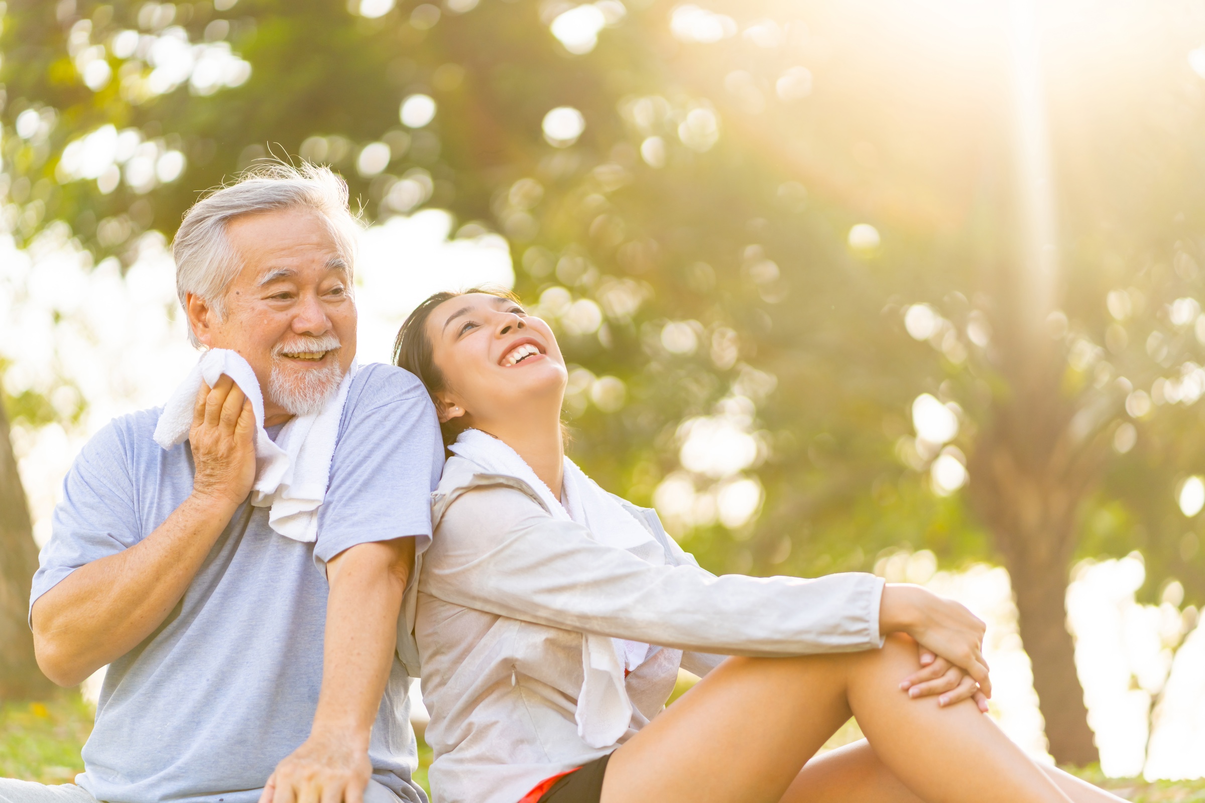 Man and younger girl sitting in the park after a workout.