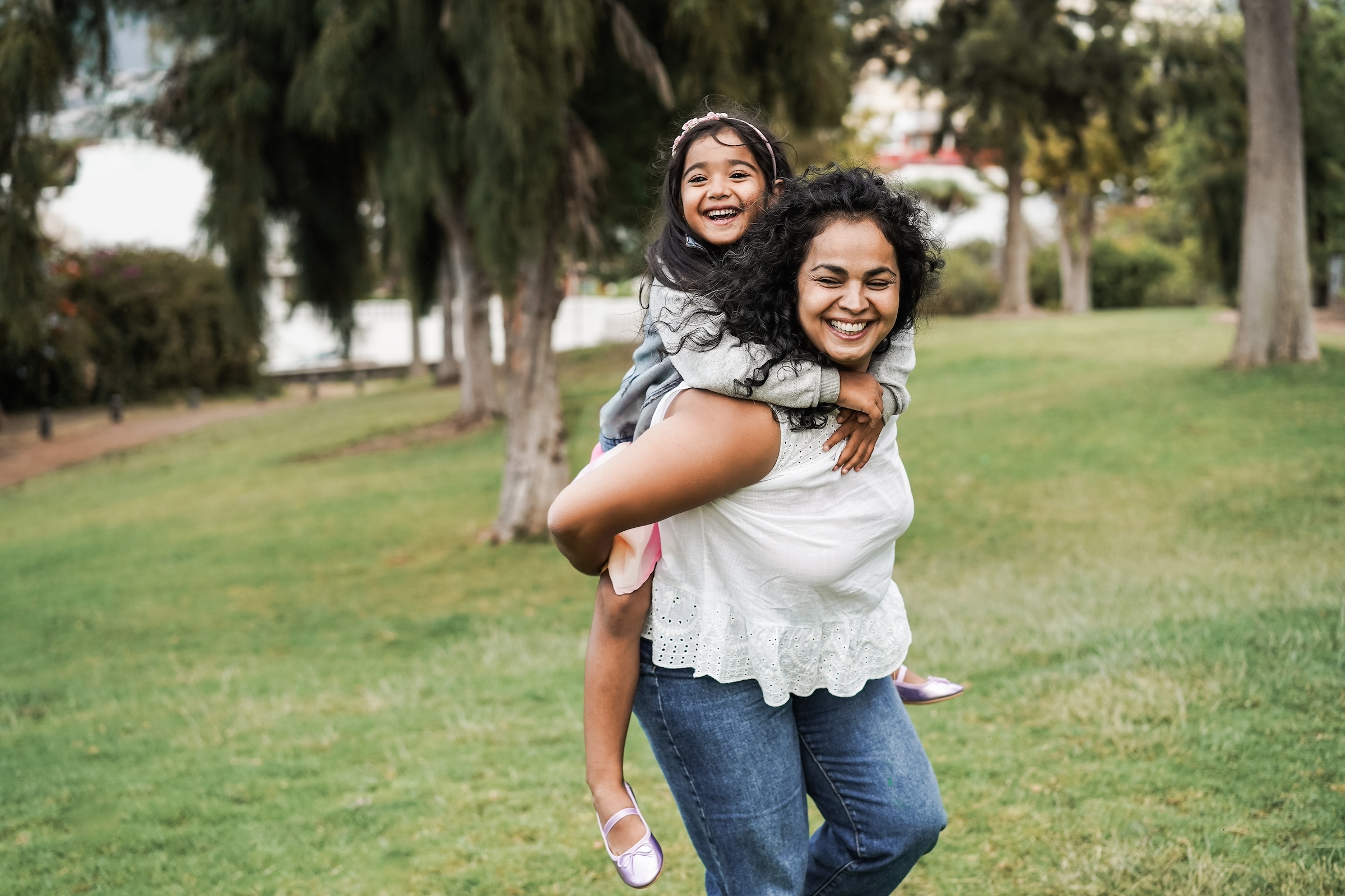 Women playing with her daughter in the grass looking happy.
