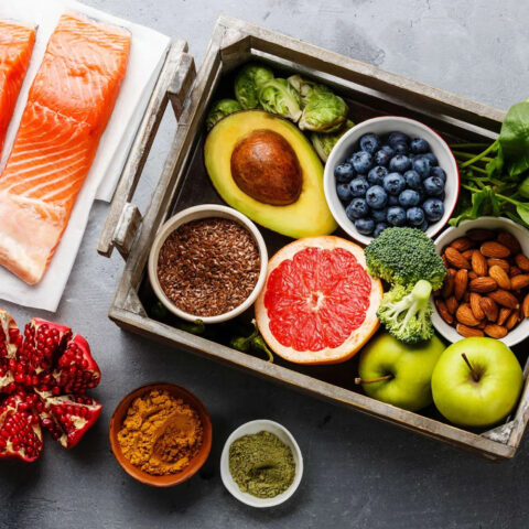 A tray of whole foods next to two salmon fillets.