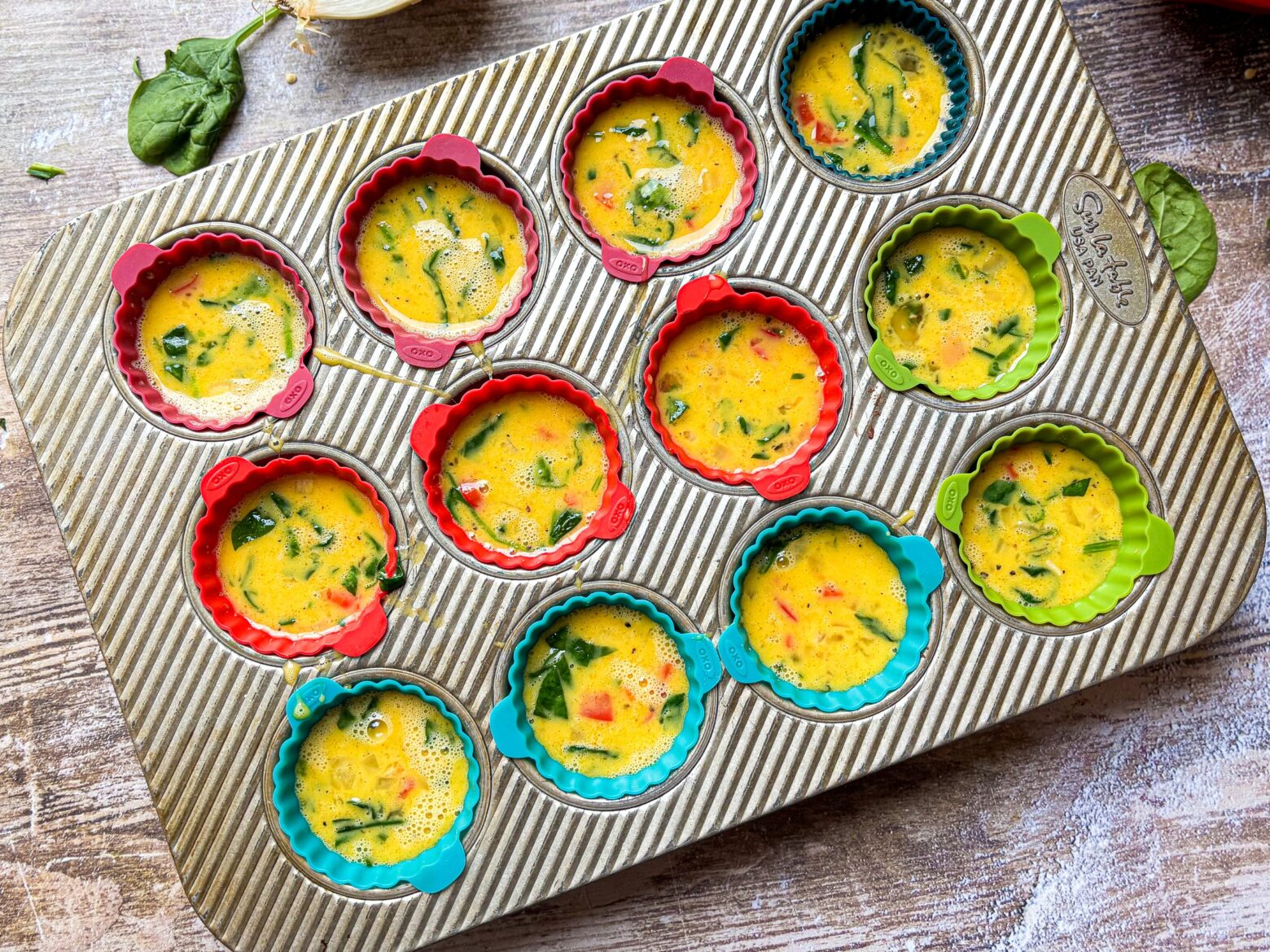 Red Pepper & Spinach Egg Bite batter in a muffin tin.