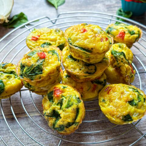 Red Pepper & Spinach Egg Bites stacked on a cooling rack.