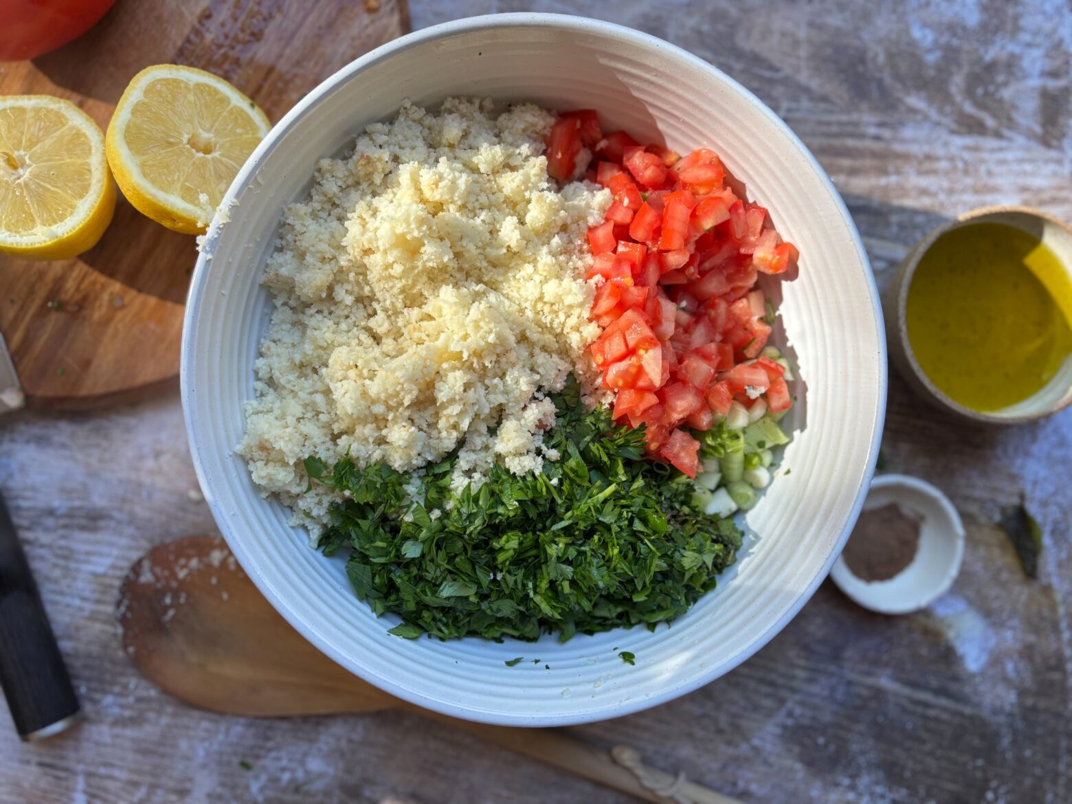 Prepped ingredients for Cauliflower Tabouli Salad separated in the same bowl.
