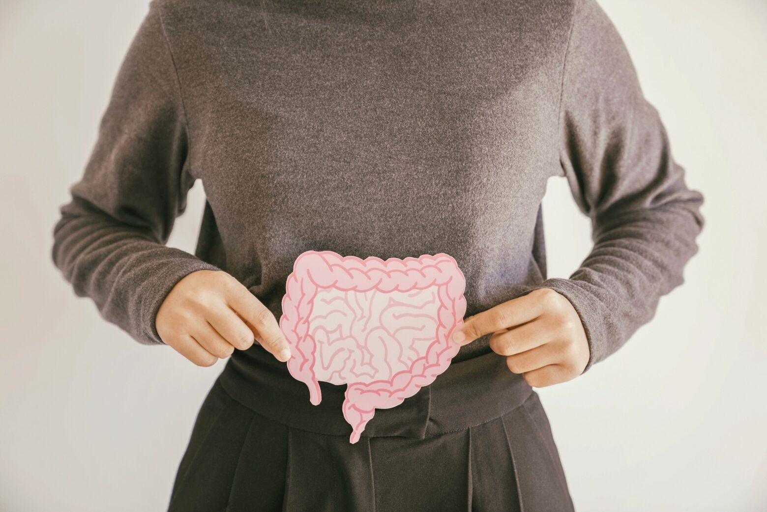 Woman holding a cutout diagram of an intestine over her abdomen.