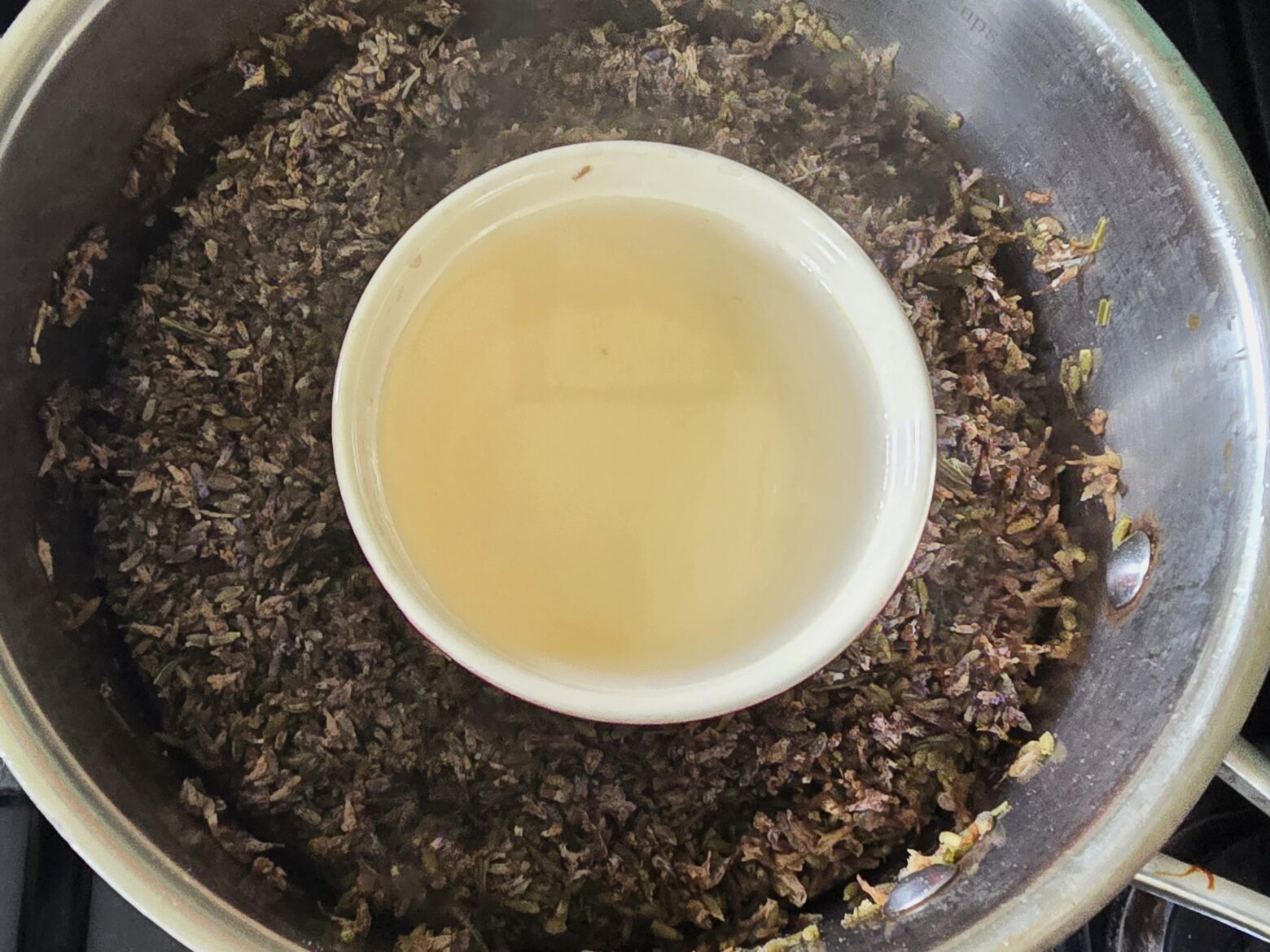 Lavender hydrosol in pot with distilled lavender flowers