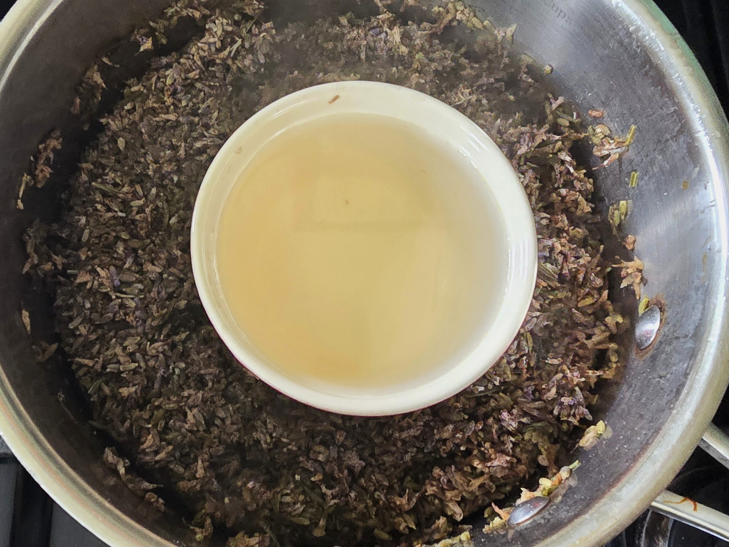 Lavender hydrosol in pot with distilled lavender flowers