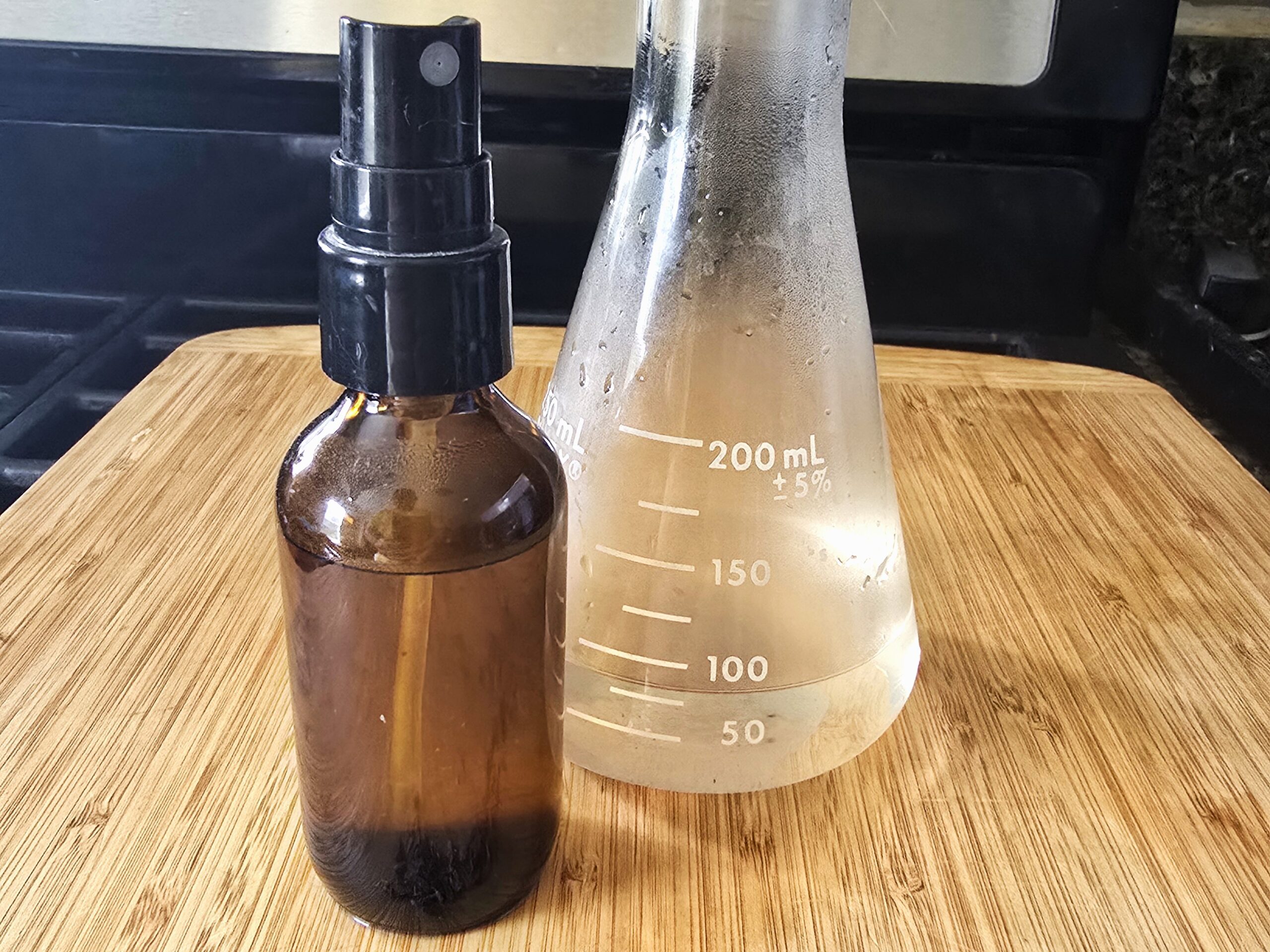 Finished Lavender Hydrosol in a spray bottle next to a measuring flask