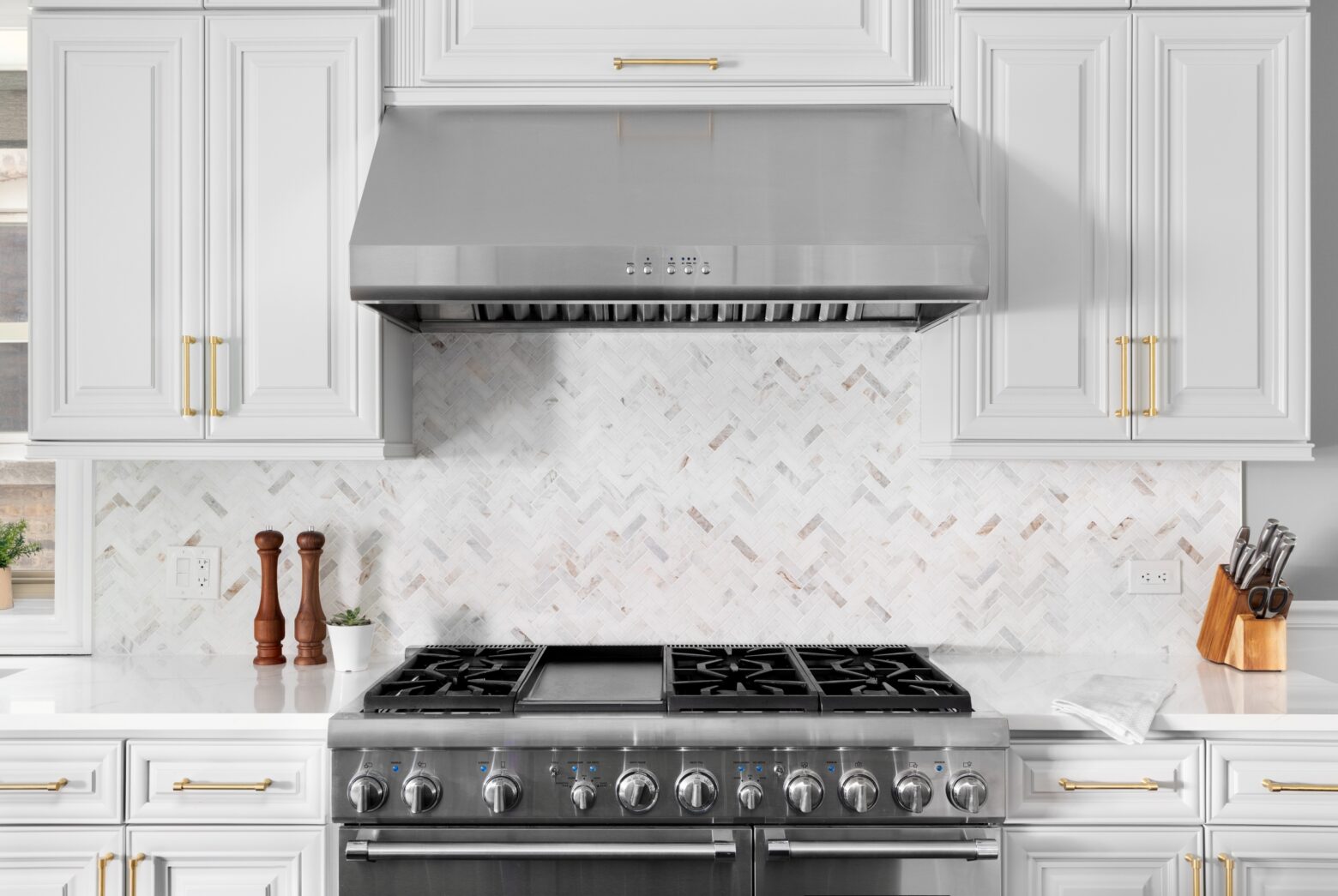 An oven range with a kitchen ventilation hood in a white kitchen.