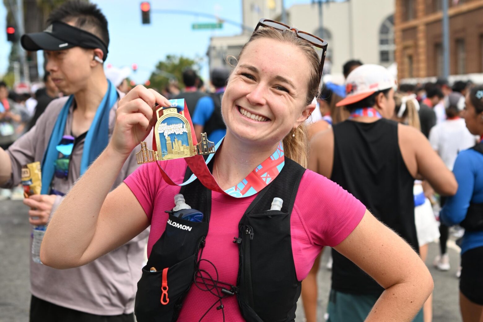 Author smiling and holding up a finisher medal for the San Francisco Marathon.