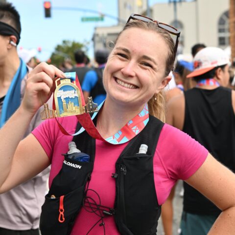 Author smiling and holding up a finisher medal for the San Francisco Marathon.