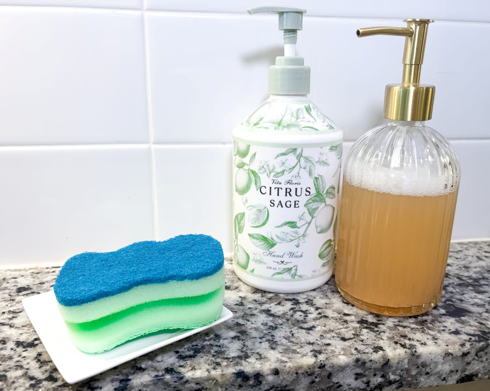 Two soap dispensers with sponges on a kitchen sink.