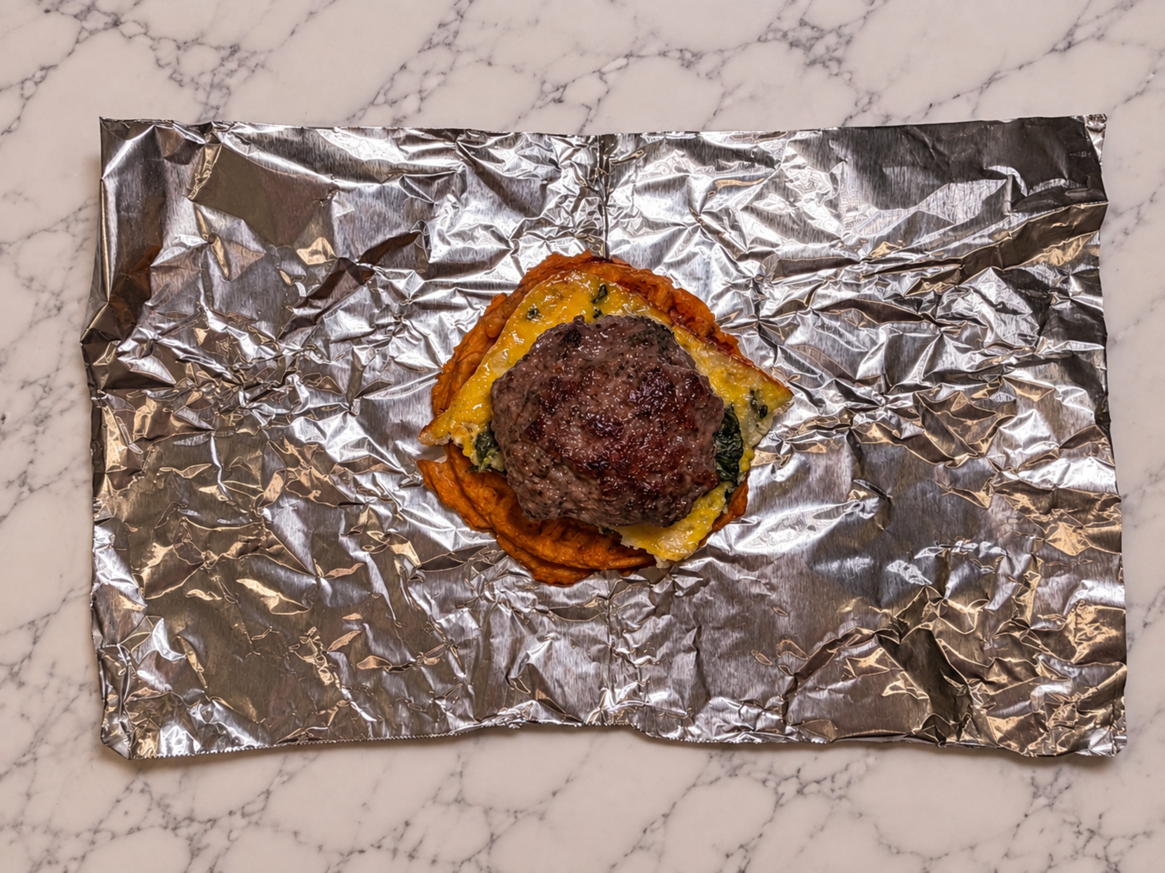Bison patty on top of an egg square and sweet potato waffle.