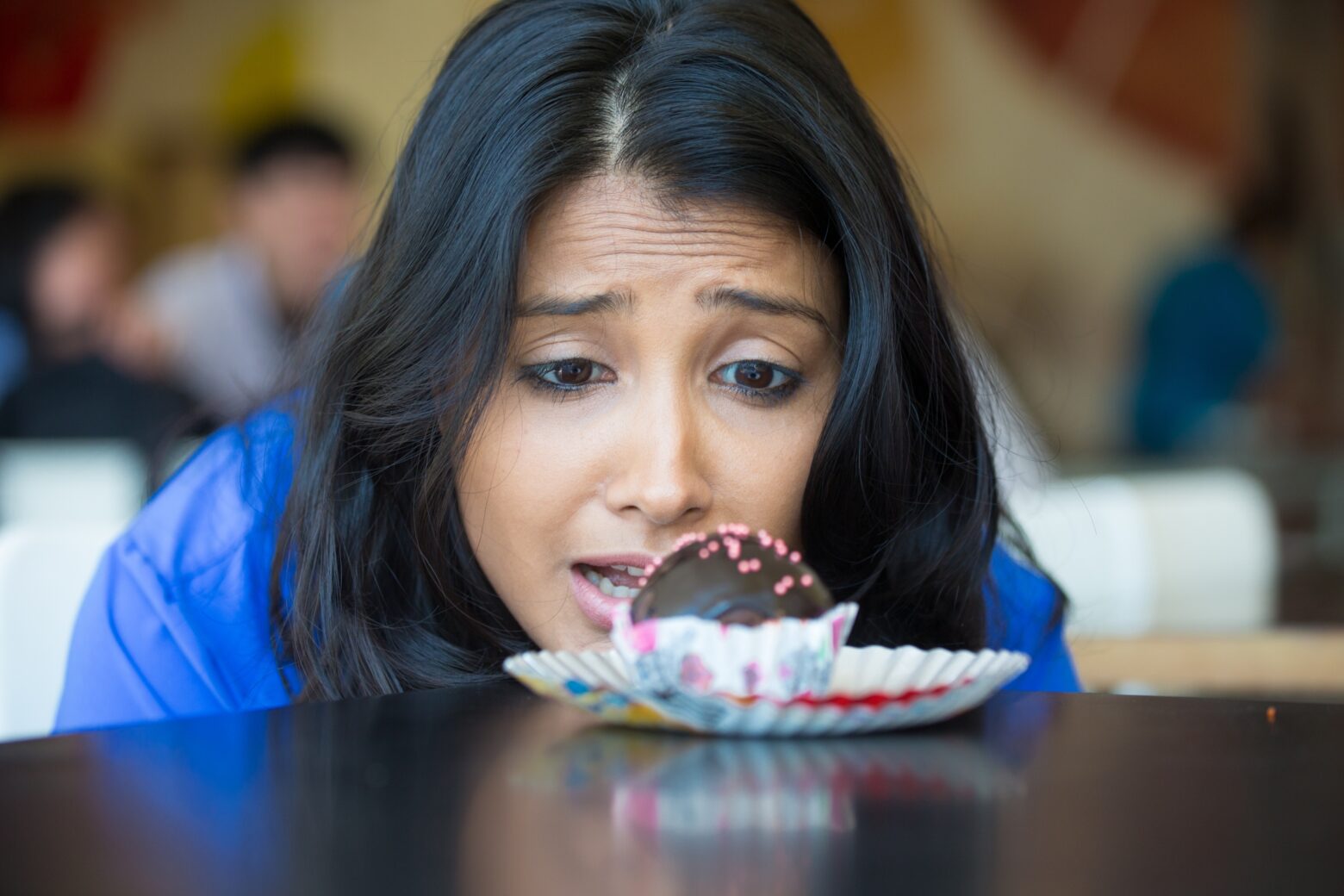 A woman looks longingly at a chocolate truffle.